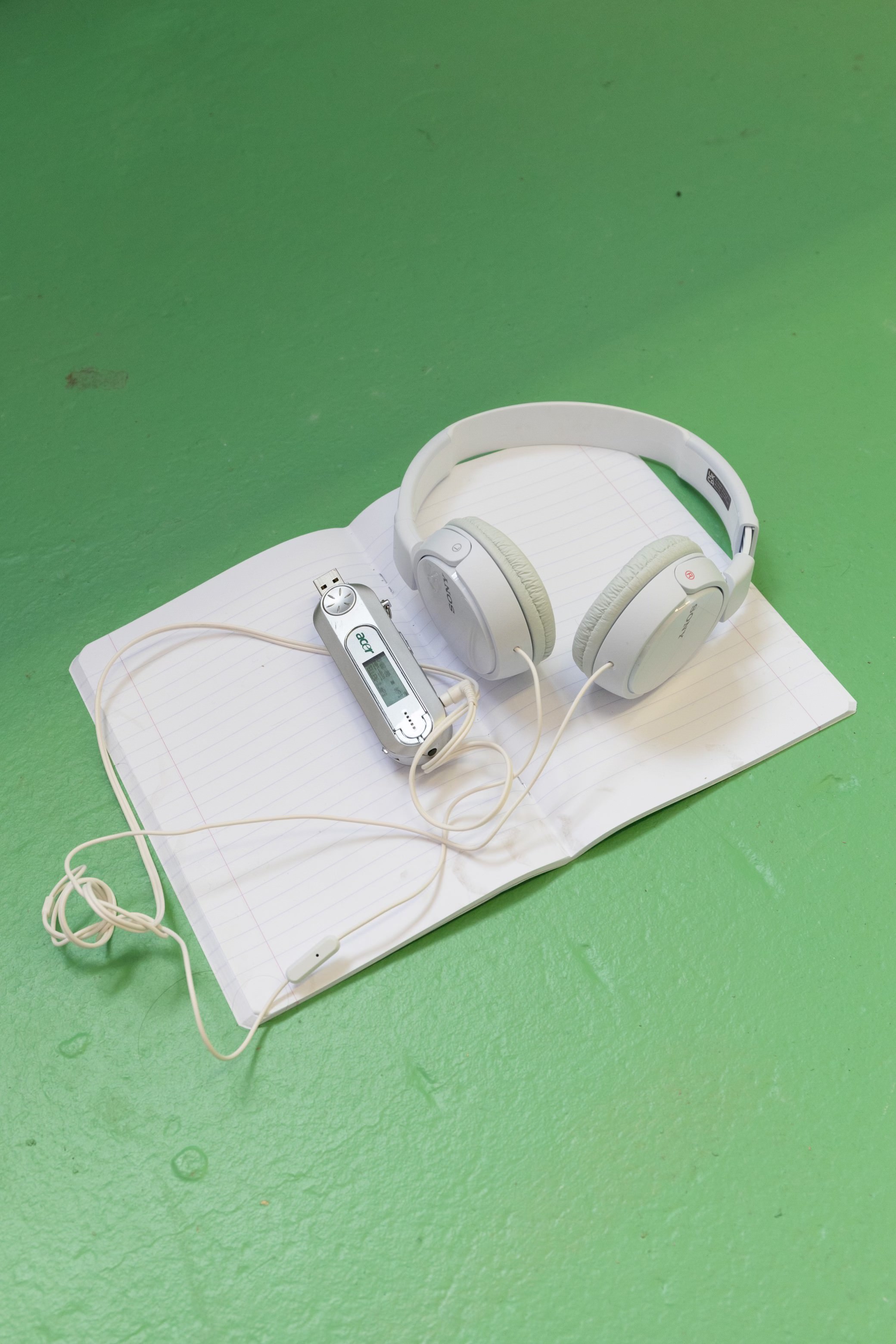 Prázdný sešit, na kterém leží sluchátka pro poslech hudby složené k dílu.